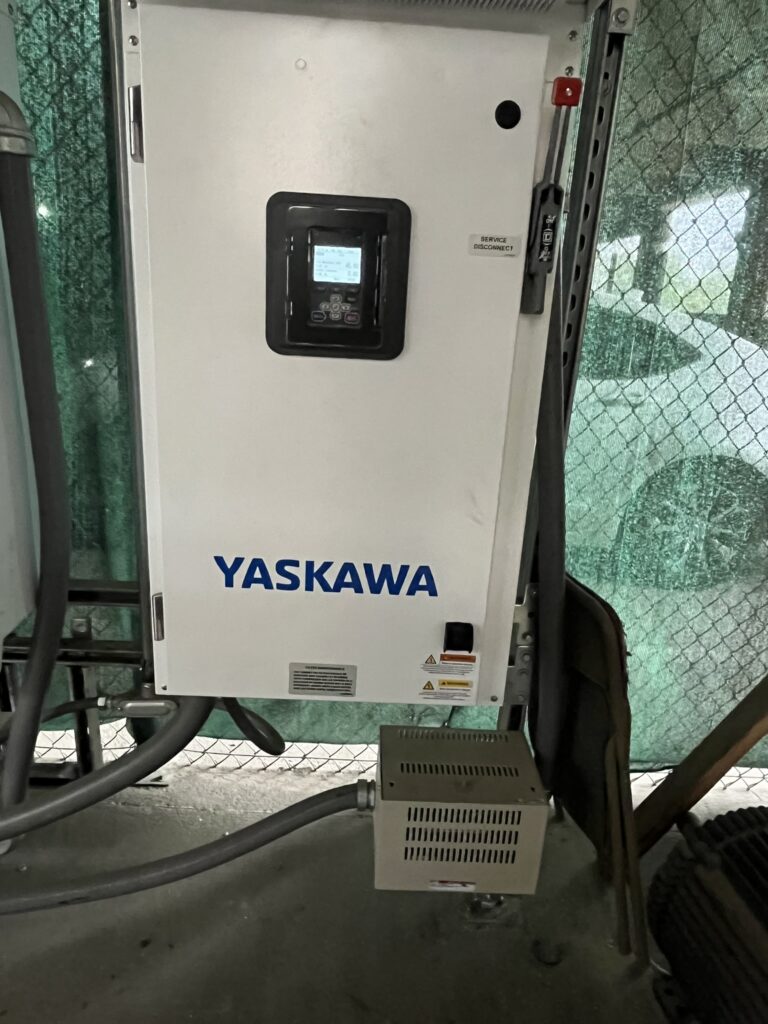 A newly installed white Yaskawa variable frequency drive and a beige line reactor connected by conduits.