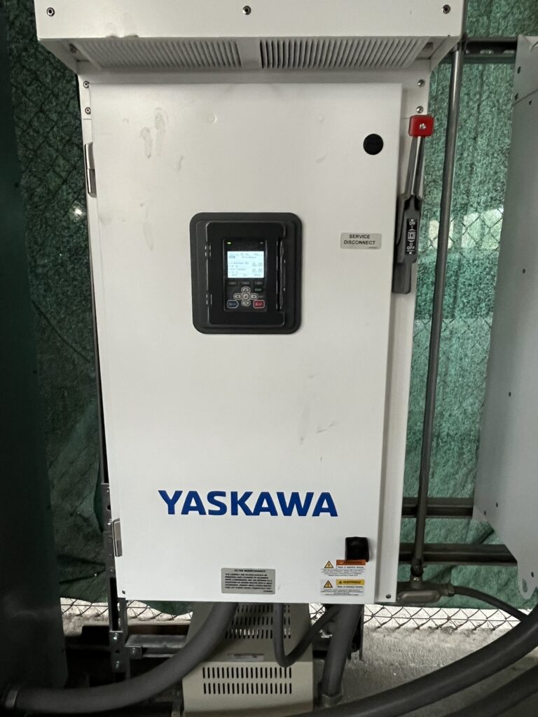 Close-up of a white Yaskawa variable frequency drive (VFD) control panel with a digital screen and a service disconnect switch.