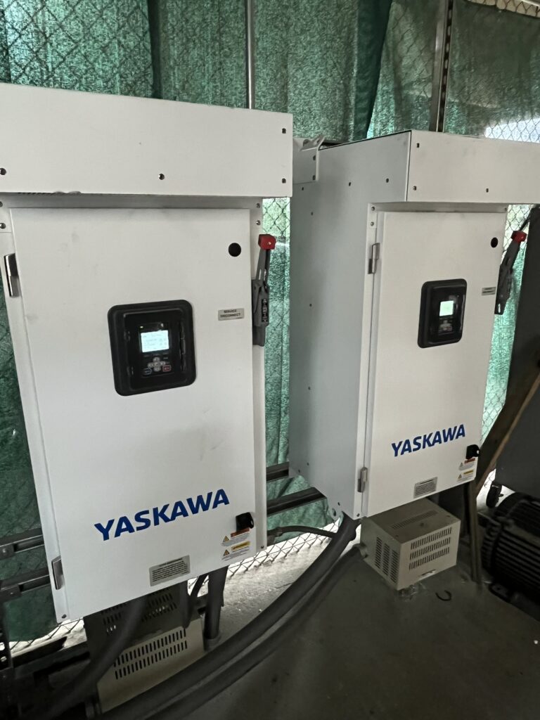 Two newly installed white Yaskawa variable frequency drives with digital displays and line reactors in a commercial setting.