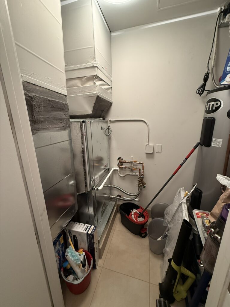 A newly installed water source heat pump unit with ductwork and copper piping in a utility closet.