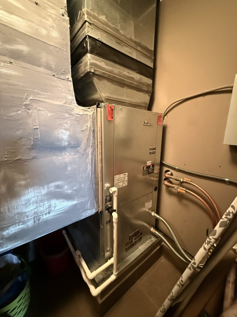 A newly installed ClimateMaster water source heat pump unit in a utility closet, connected to silver ductwork and plumbing.