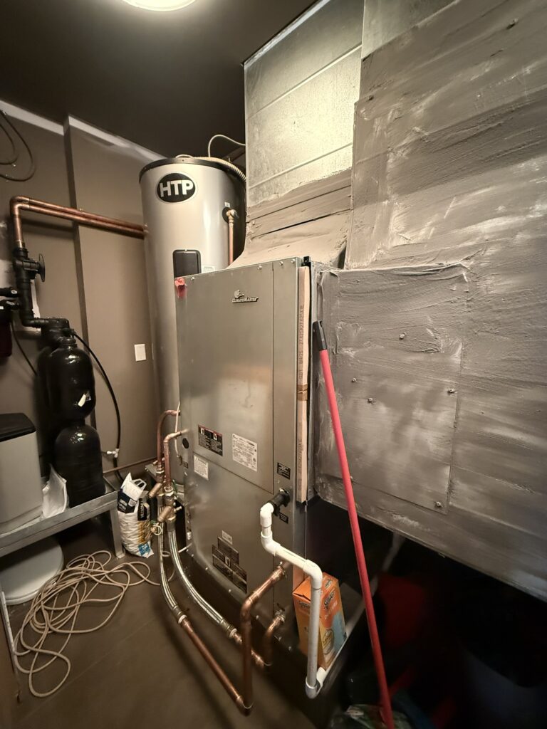 A newly installed ClimateMaster water source heat pump unit connected to an HTP water heater and ductwork in an indoor utility space.