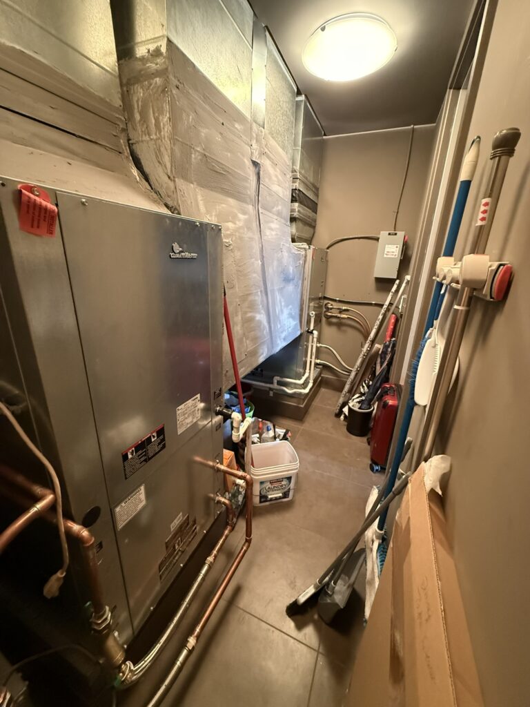 A new Climatemaster water source heat pump unit with copper piping and sealed metal ductwork in a utility closet.
