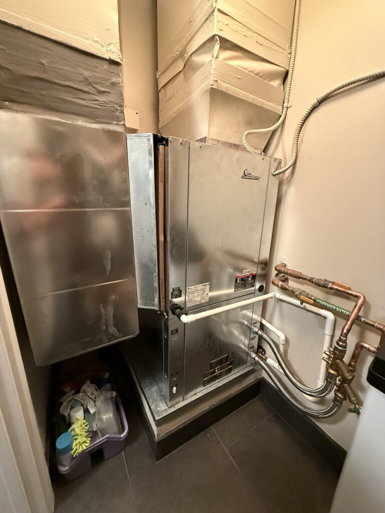 A new Climatemaster water source heat pump unit installed in an indoor utility closet, with ductwork and plumbing connections.