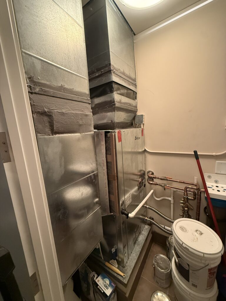 A new Climatemaster water source heat pump unit and associated ductwork and plumbing lines are installed in a utility closet.