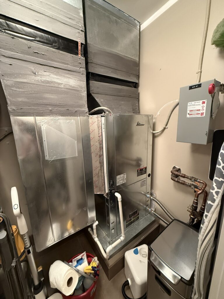 A newly installed Goodman water-source heat pump unit with connected ductwork and copper piping in an indoor utility closet.