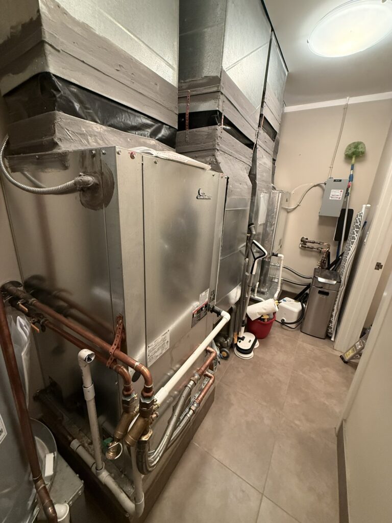 Newly installed water source heat pump units with copper and PVC piping and ductwork in an indoor mechanical room.