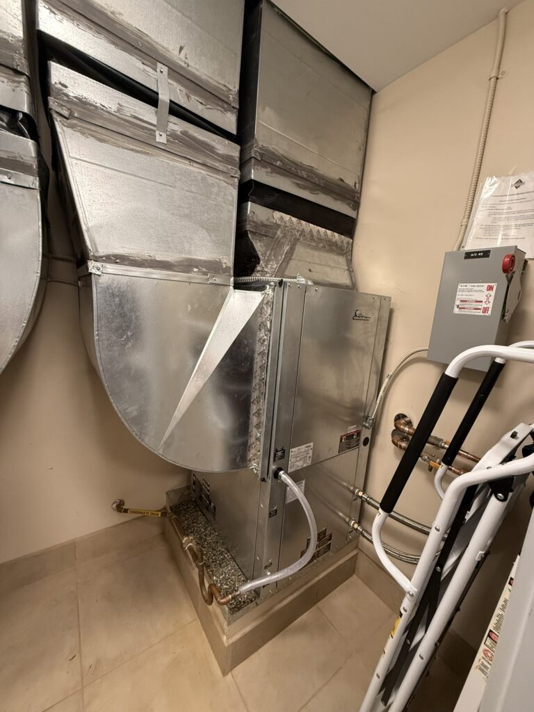 Newly installed indoor water source heat pump unit connected to metal ductwork in a utility closet.