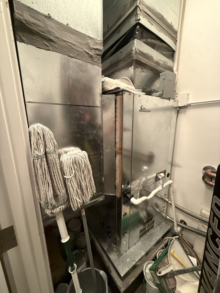 A new Climatemaster water source heat pump unit connected to metal ductwork in an indoor utility closet.