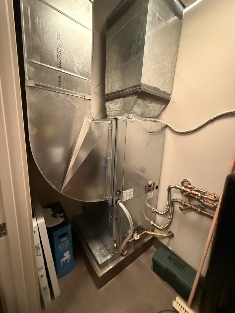 Newly installed Climatemaster water source heat pump unit with sheet metal ductwork and copper piping in a utility closet.