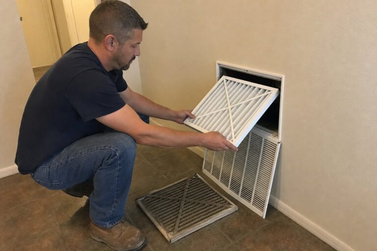 A man replaces a dirty HVAC air filter with a clean one in a wall return vent, showing the importance of regular maintenance.